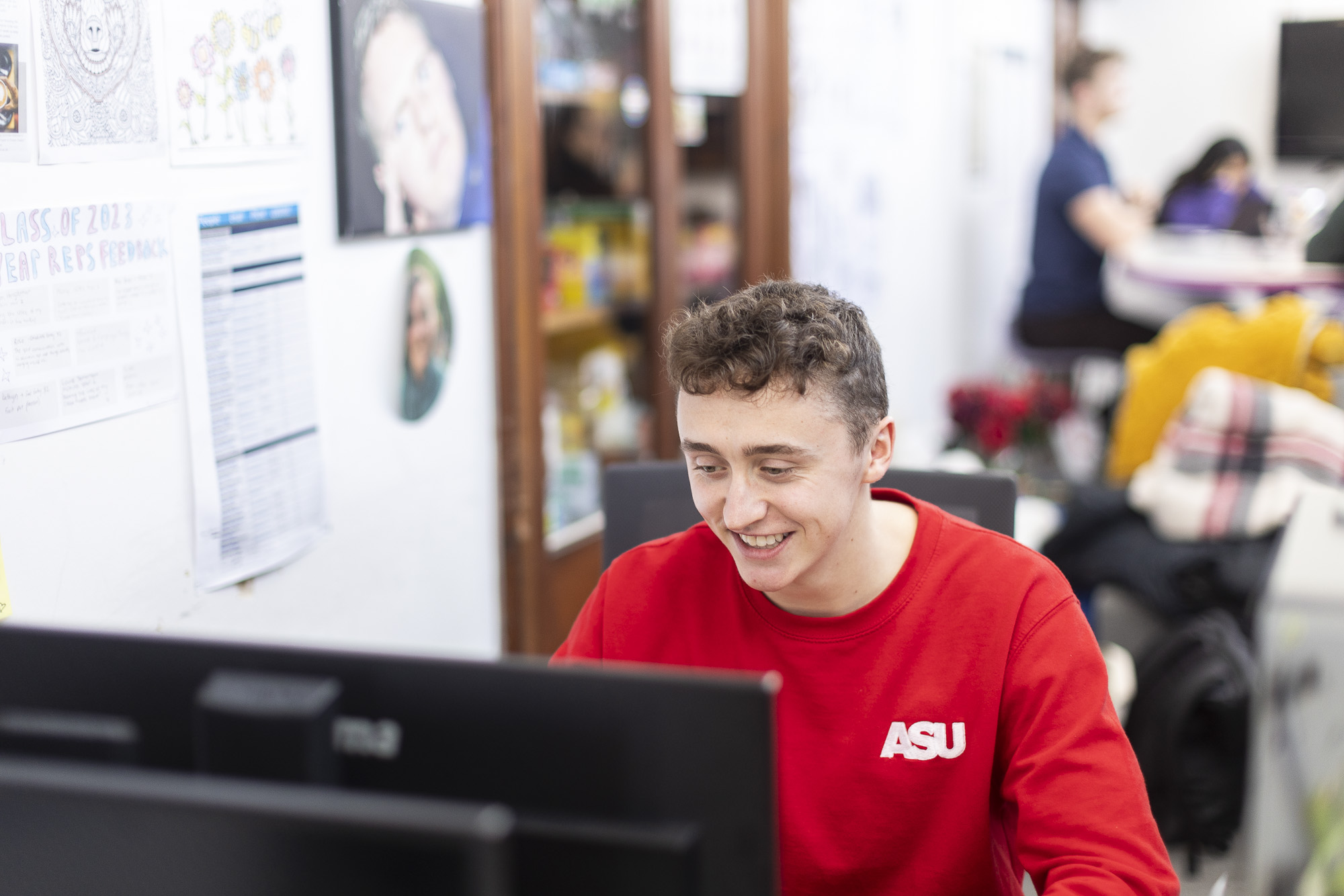 SU student wearing a red jumper using his computer