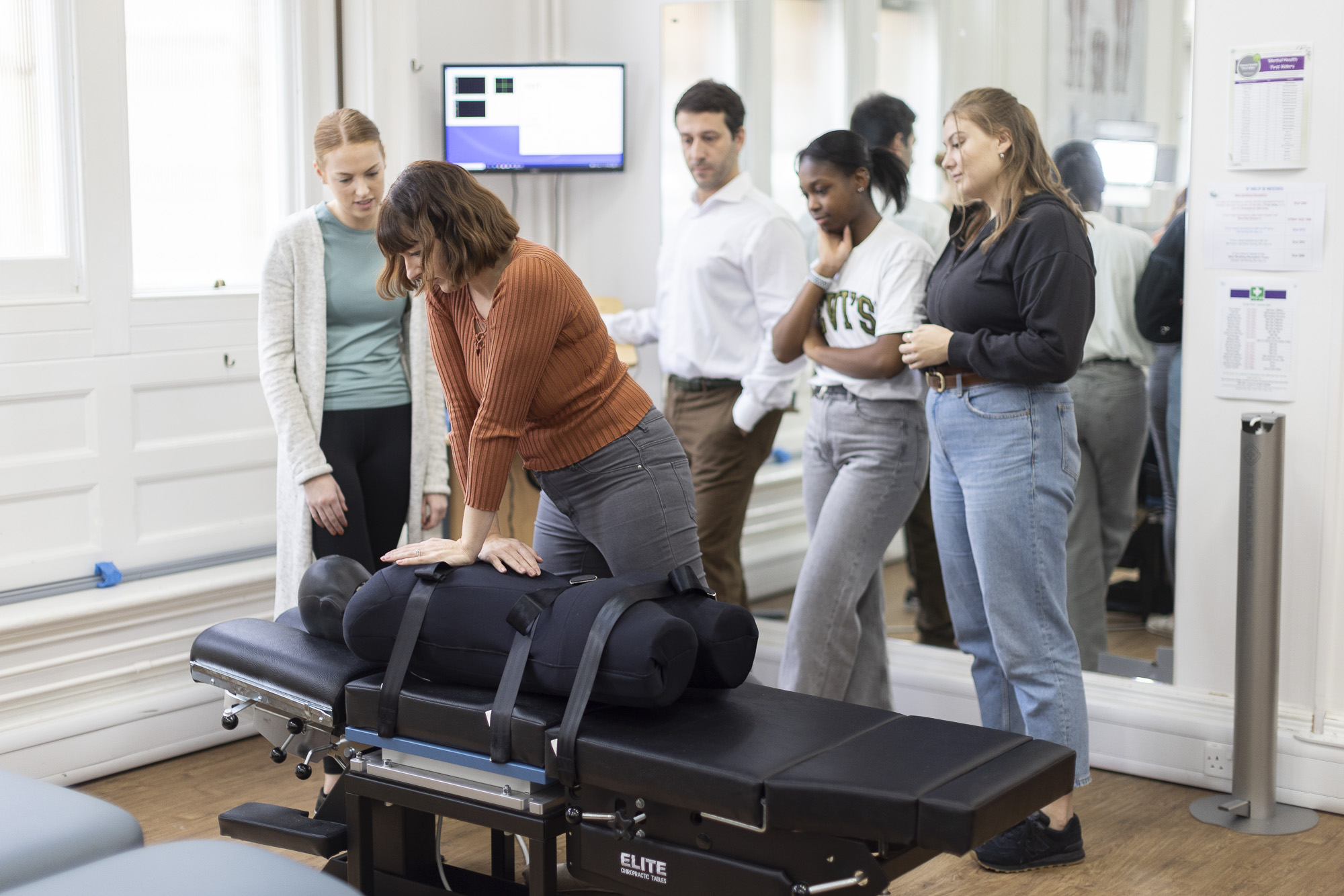Chiropractic practical class - lecturer demonstrating technique to students watching